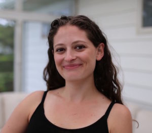 Rachel smiles at camera in black tank top with long dark hair